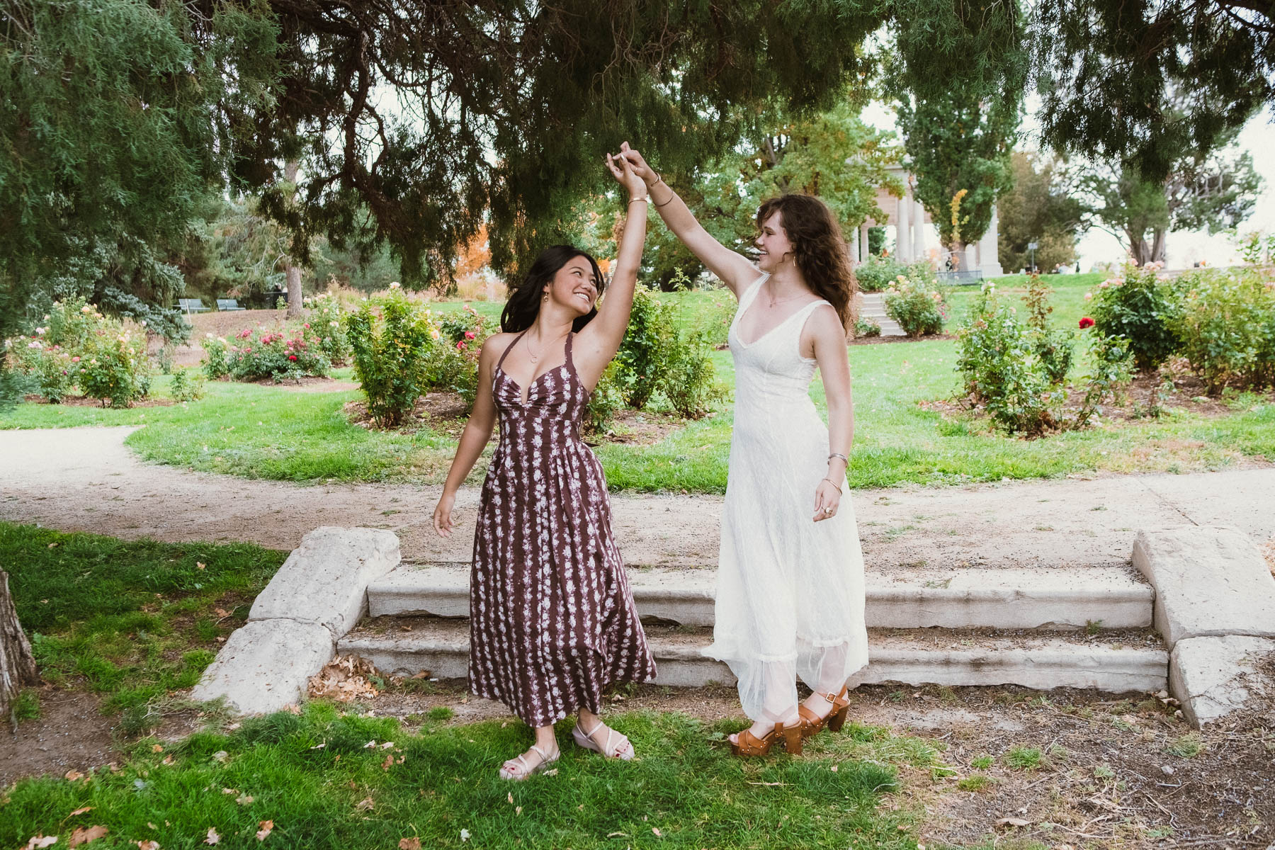 Two friends playfully twirling together in a garden